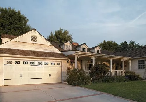 Two-car garage with white garage door attached to home with long front porch to the right.