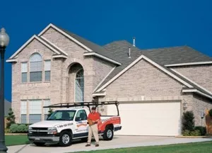 White two-car garage on large brick home.