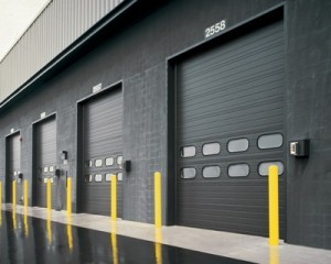 Row of black sectional steel doors on a commercial building.